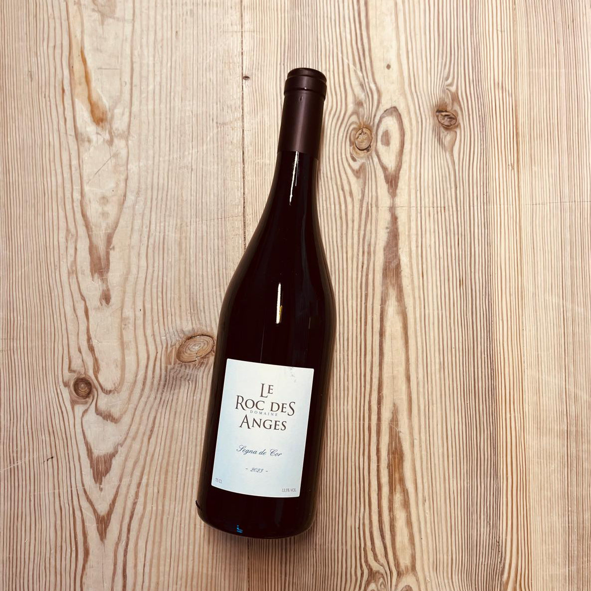 Wine bottle labeled 'Le Roc des Anges' on a wooden surface