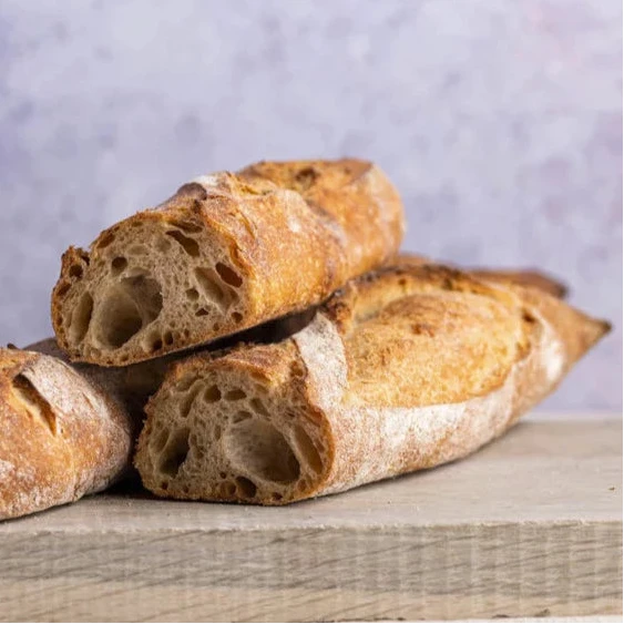 large cuts of sourdough baguette on a wooden board.