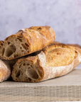 large cuts of sourdough baguette on a wooden board.