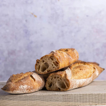 large cuts of sourdough baguette on a wooden board.