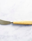 A wooden handled butter knife on a marble worktop.