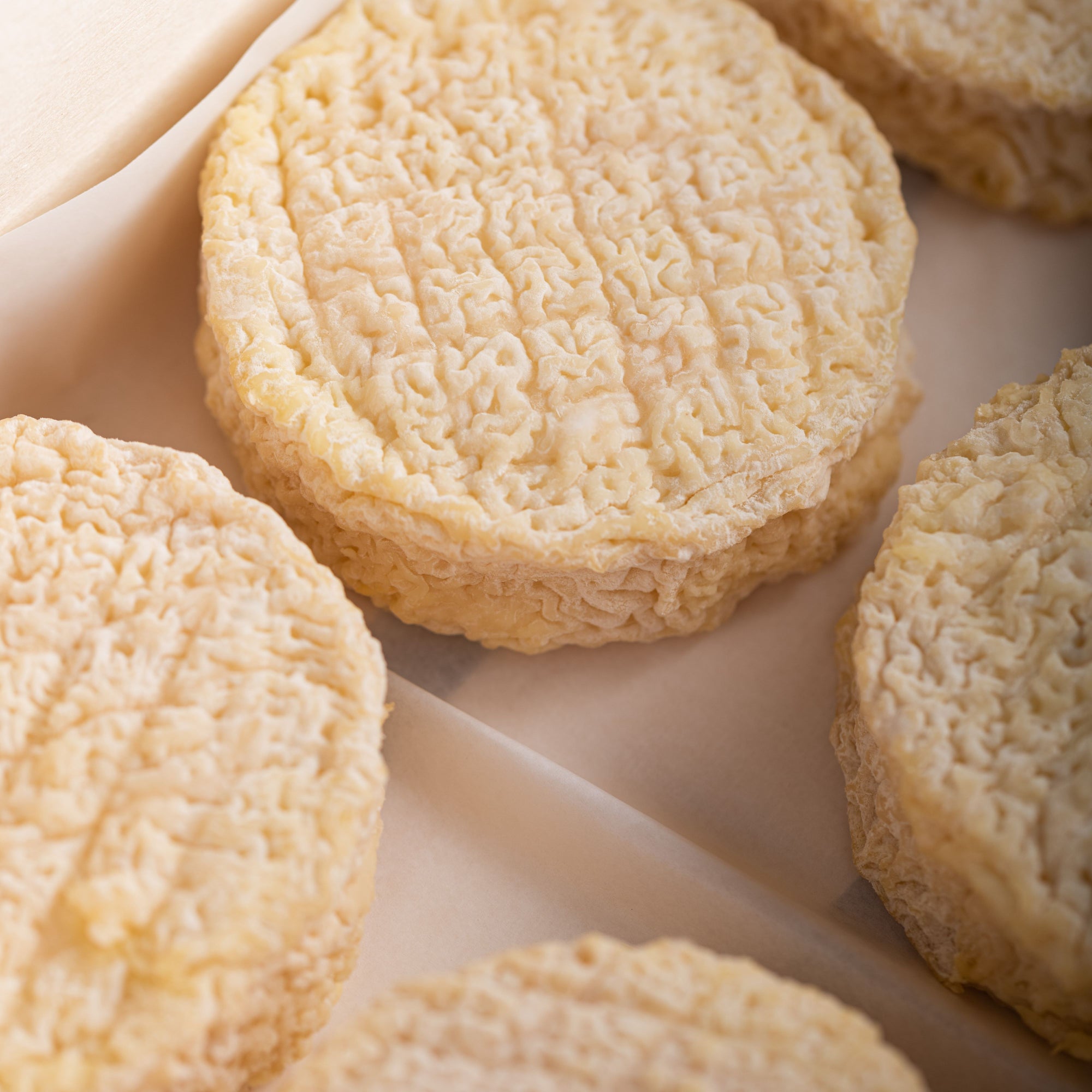 Close up of the creamy coloured wrinkly rind of Brefu Bach ewe's milk cheese.
