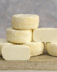 Cut and whole pieces of Castillon Frais fresh goat's cheese on a wooden board.