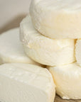 Close up of cut and whole pieces of Castillon Frais fresh goat's cheese on a wooden board.