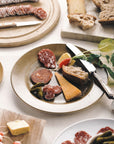 A plate containing a selection of cheese, charcuterie and bread.