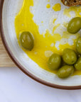A plate of green olives with olive oil.