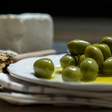 Intosso green olives on a white plate.