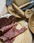 Slices of 'Jesus' salami with some slices of bread on a wooden board.