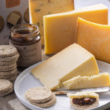 A plate of lancashire cheese with oatcakes and pickle.