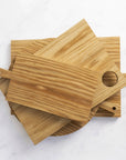 A stack of wooden chopping boards of various sizes on a marble worktop.