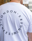 The back of a man wearing a white t-shirt with a printed round London Cheesemongers logo.