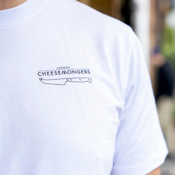 The chest of a man in a white t-shirt wih a straight London Cheesemongers and knife logo over the breast area.