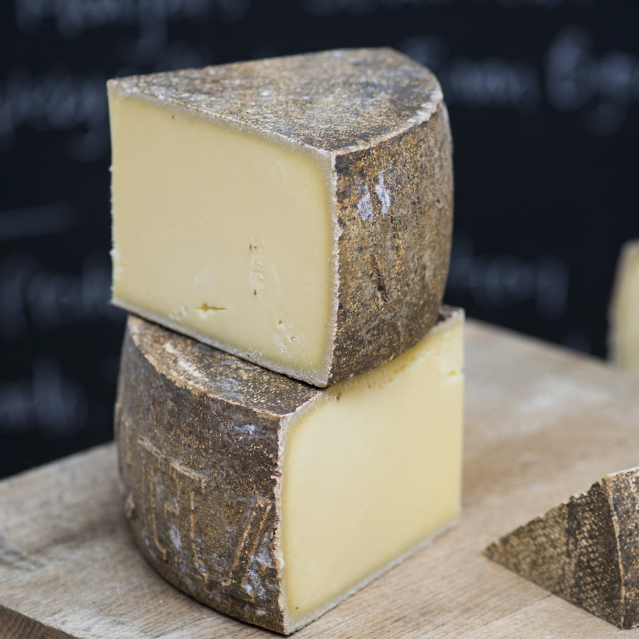 Cuts of Le Marechal hard cow's milk cheese on a wooden board.