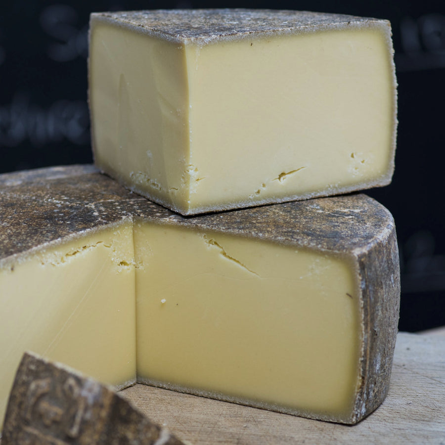 Various sized cuts of Le Marechal hard cow's milk cheese on a wooden board.