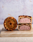 A cut and whole pork pie on a wooden chopping board.