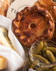 A selection of cheeses, cornichons and a pork pie.