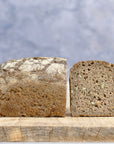 A rye loaf of bread cut in half and on a wooden board. 