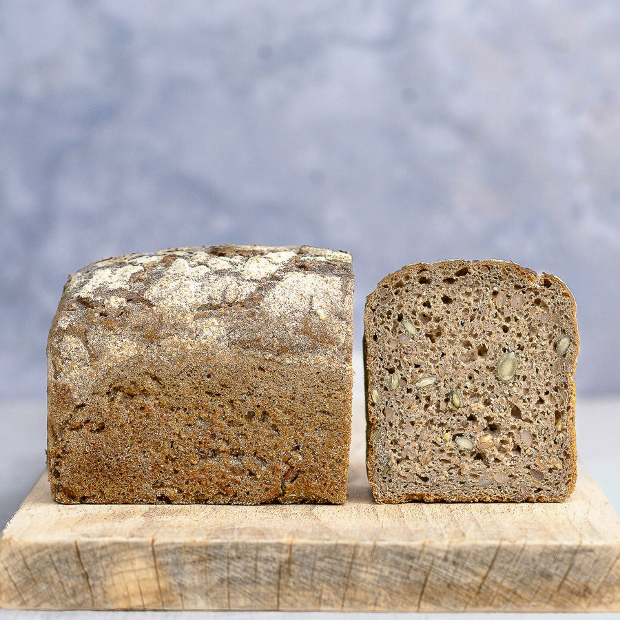 A rye loaf of bread cut in half and on a wooden board. 