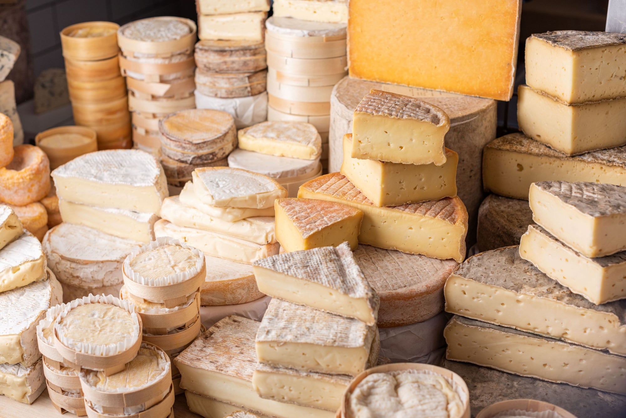 A selection of cut and whole cheeses on a shop counter