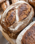Loaves of brown sourdough bread stacked up on a table.