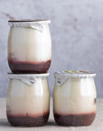 Glass jars of strawberry compote fruit yoghurt.