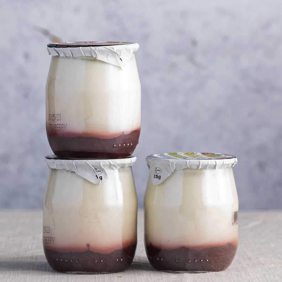 Glass jars of strawberry compote fruit yoghurt.