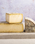 Cuts of Tomme de Savoie cheese on a wooden board.