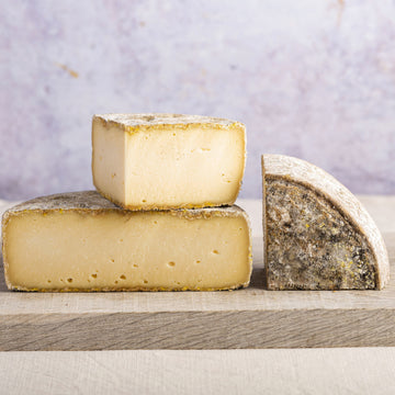 Cuts of Tomme de Savoie cheese on a wooden board.