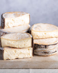 Cut and whole pieces of Little Rollright cheese on a wooden chopping board.