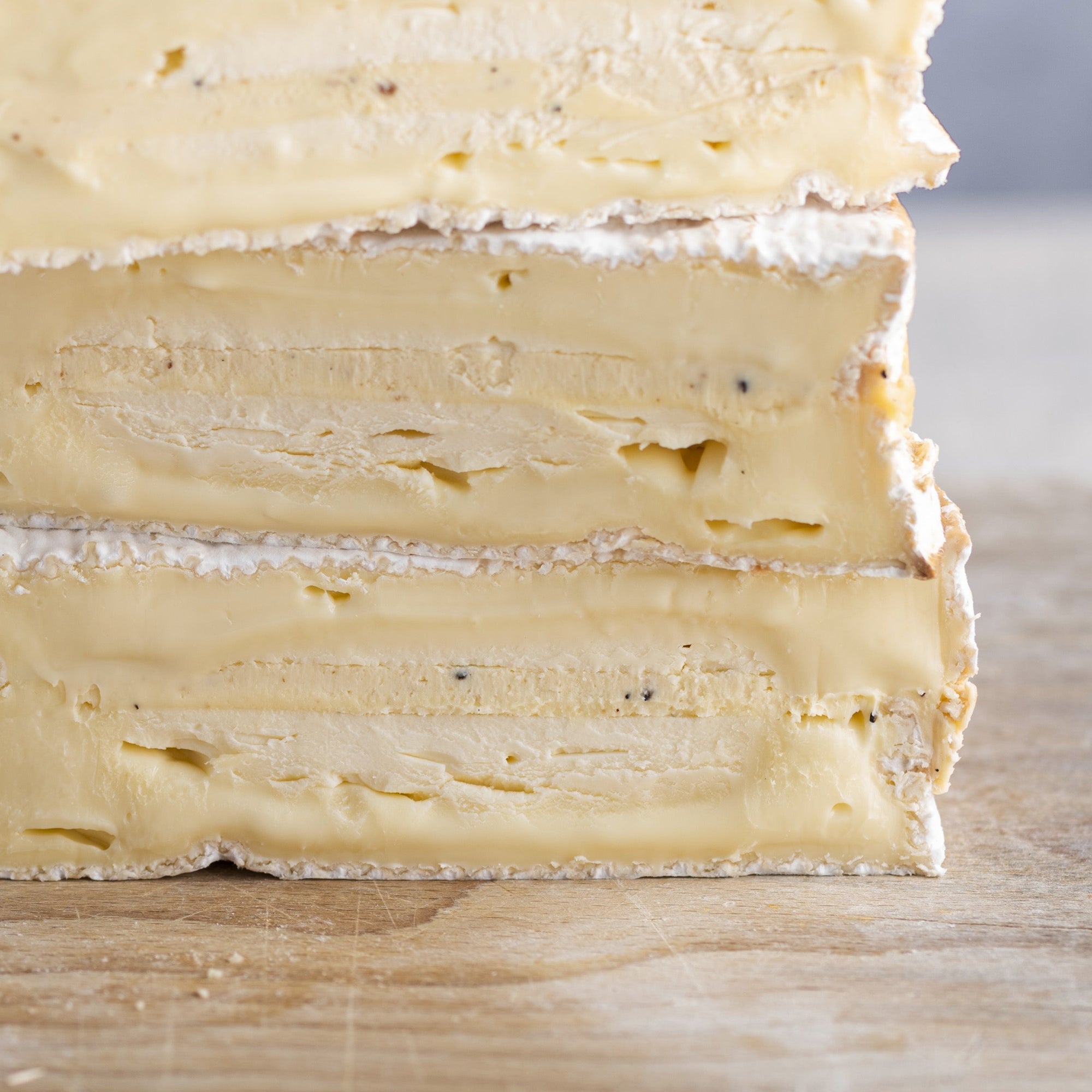 A close up of the cut side of baron bigod truflled cheeseon a wooden board.