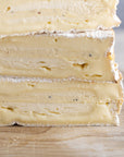 A close up of the cut side of baron bigod truflled cheeseon a wooden board.