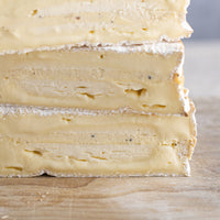 A close up of the cut side of baron bigod truflled cheeseon a wooden board.