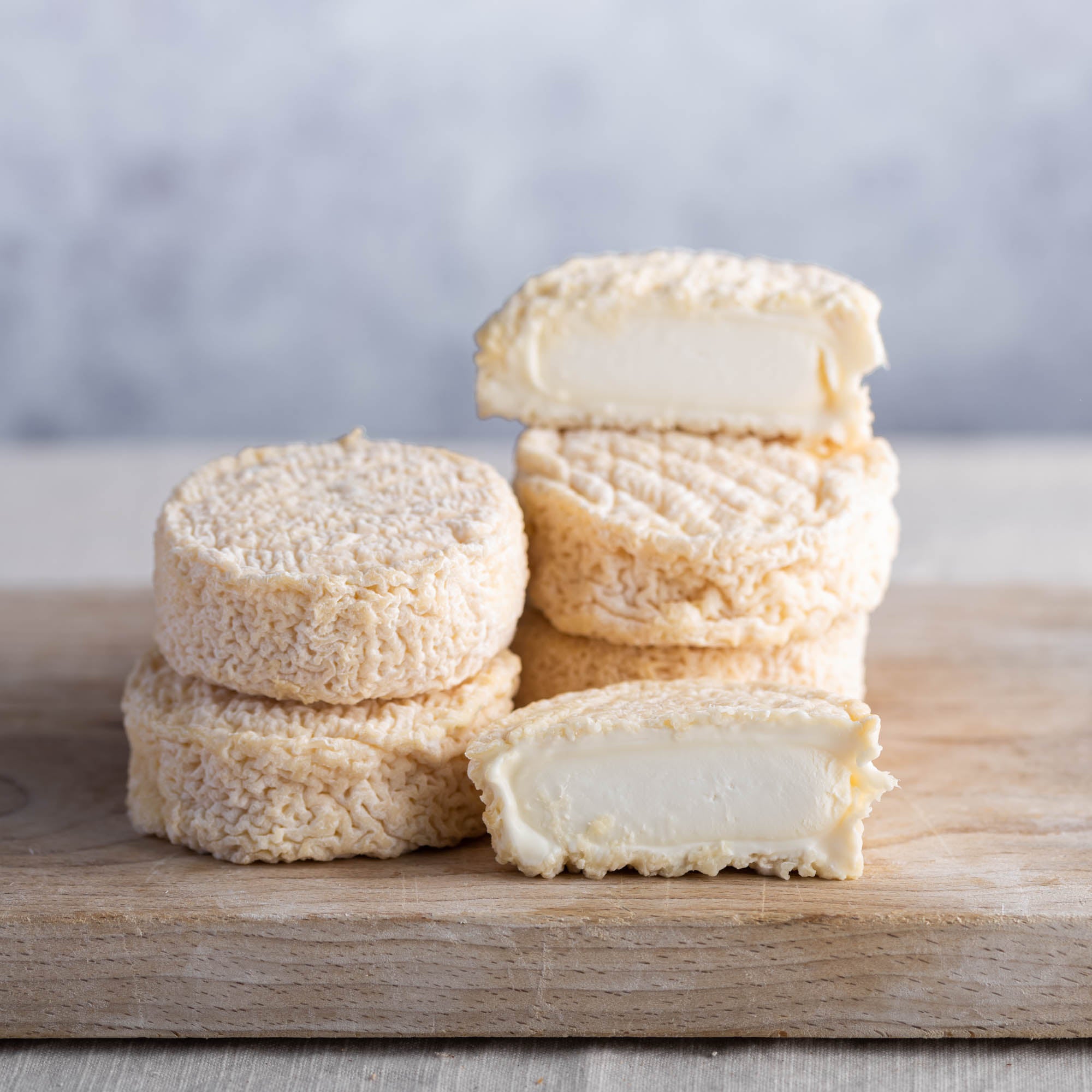 Cut and whole Brefu Bach ewe's milk cheeses on a wooden board.