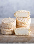 Cut and whole Brefu Bach ewe's milk cheeses on a wooden board.