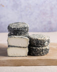 Cut and whole pieces of brightwell ash goat cheese stacked up on a wooden board.