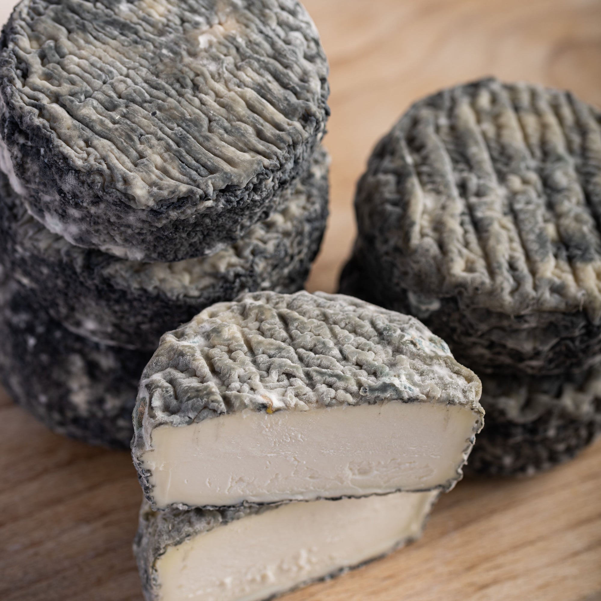 A cut and whole brightwell ash goats cheese on a wooden board.