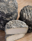 A cut and whole brightwell ash goats cheese on a wooden board.