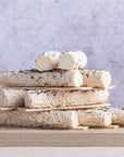 Stack of Buchette de Manon goat's cheeses on a wooden board.