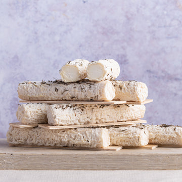 Stack of Buchette de Manon goat's cheeses on a wooden board.