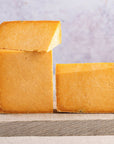 Cut pieces of orange cheshire cheese on a wooden board.