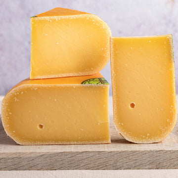 Cut pieces of Coolea cheese on a wooden board.