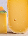A close up of the cut face of a piece of Coolea cheese on a wooden board. 
