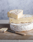 Cuts of Coulommiers on a whole cheese on a wooden board.