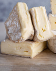 Cut pieces of Coulommiers cheese on a wooden board.