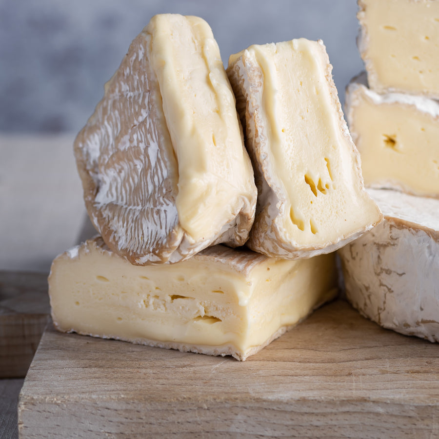 Cut pieces of Coulommiers cheese on a wooden board.