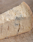 A piece of gorgonzola blue cheese on a wooden chooping board.