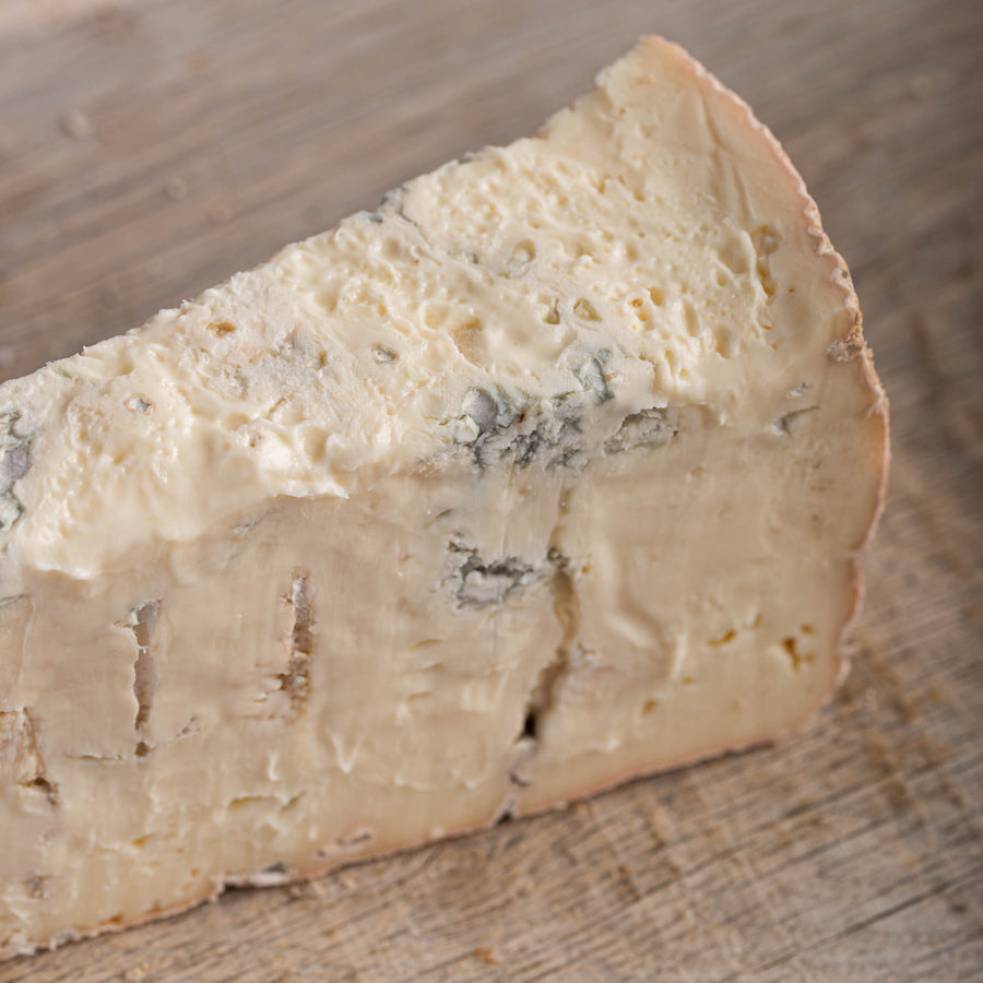 A piece of gorgonzola blue cheese on a wooden chooping board.