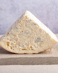 A large piece of gorgonazola blue cheese on a wooden board.