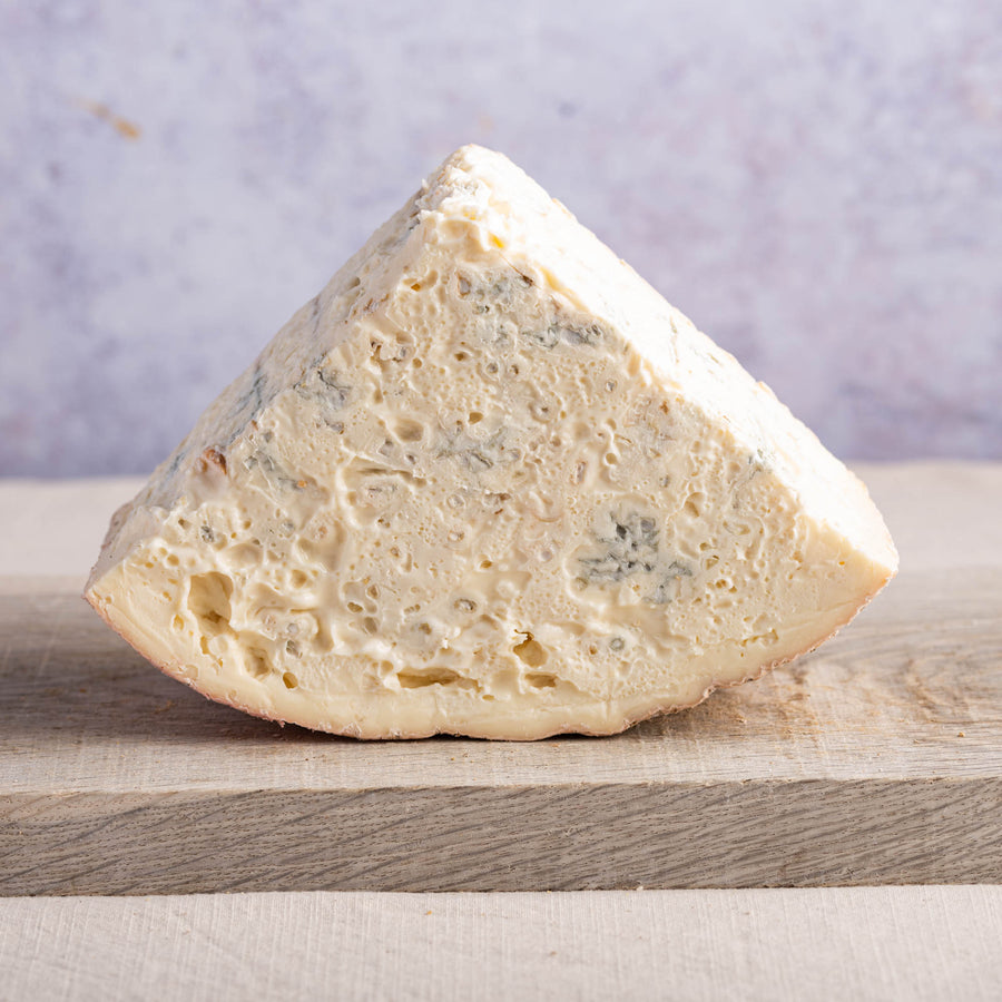 A large piece of gorgonazola blue cheese on a wooden board.