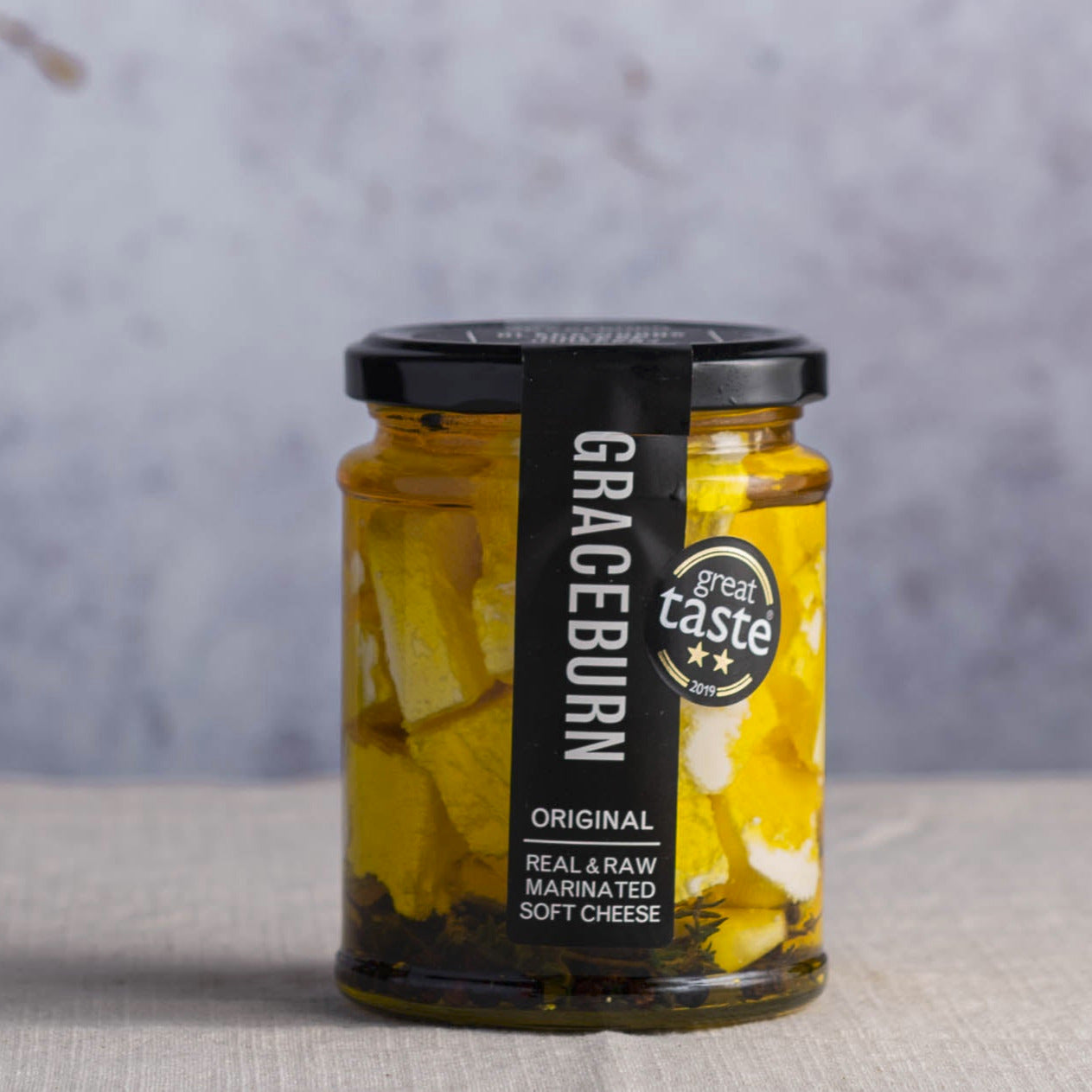 A jar of graceburn feta style cheese marinated in aromatic herb infused oil.